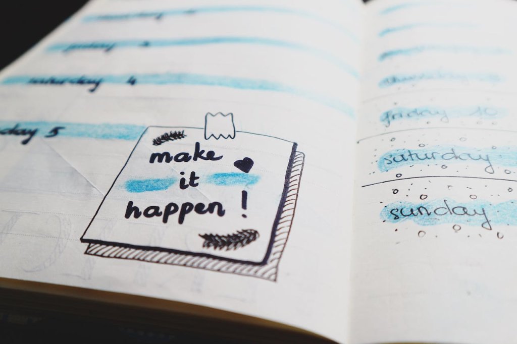 Imagem de um caderno com a frase Make it Happen desenhado em azul e preto